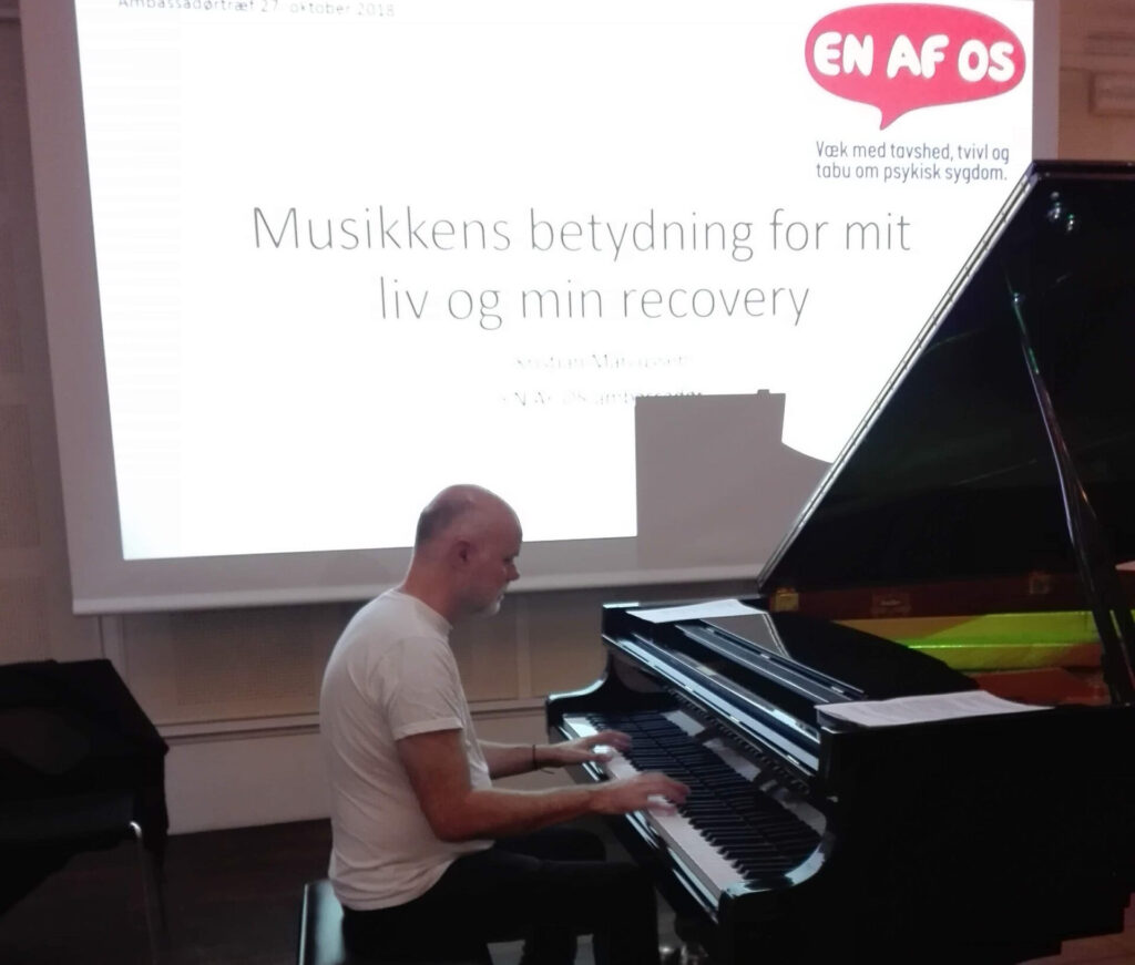 Kristian Marcussen ved flygel under foredrag om musikkens betydning for sit liv